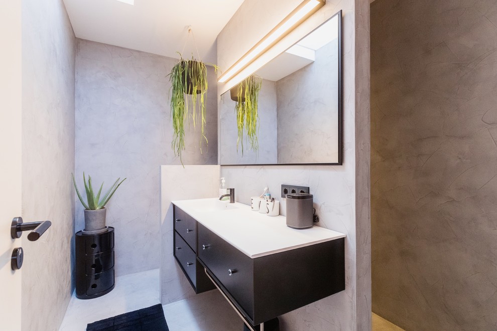 Kleines Modernes Duschbad mit bodengleicher Dusche, Wandtoilette, grauen Fliesen, grauer Wandfarbe, Betonboden, grauem Boden und weißer Waschtischplatte in Frankfurt am Main