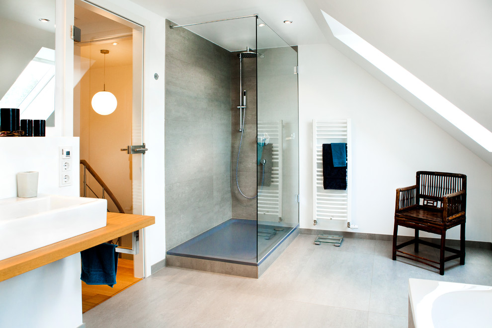 Свежая идея для дизайна: большая ванная комната в современном стиле с угловым душем, серой плиткой, плиткой из листового камня, белыми стенами, настольной раковиной, столешницей из дерева, накладной ванной, инсталляцией, открытым душем и серым полом - отличное фото интерьера