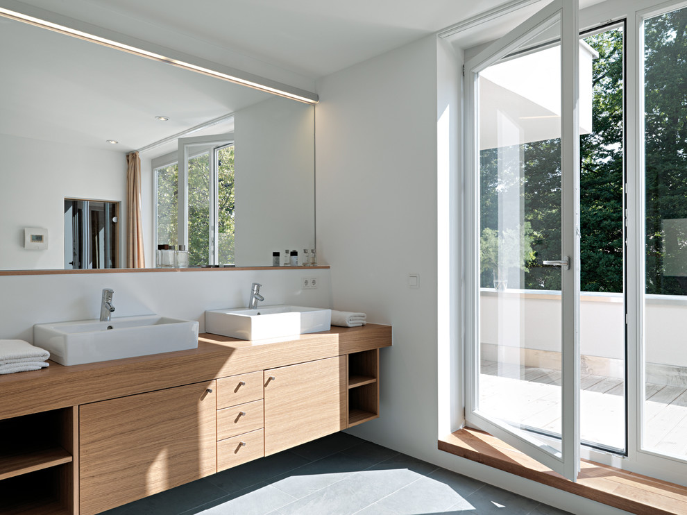 Mittelgroßes Modernes Badezimmer mit flächenbündigen Schrankfronten, hellen Holzschränken, grauen Fliesen, weißer Wandfarbe, Schieferboden, Aufsatzwaschbecken und Waschtisch aus Holz in Stuttgart