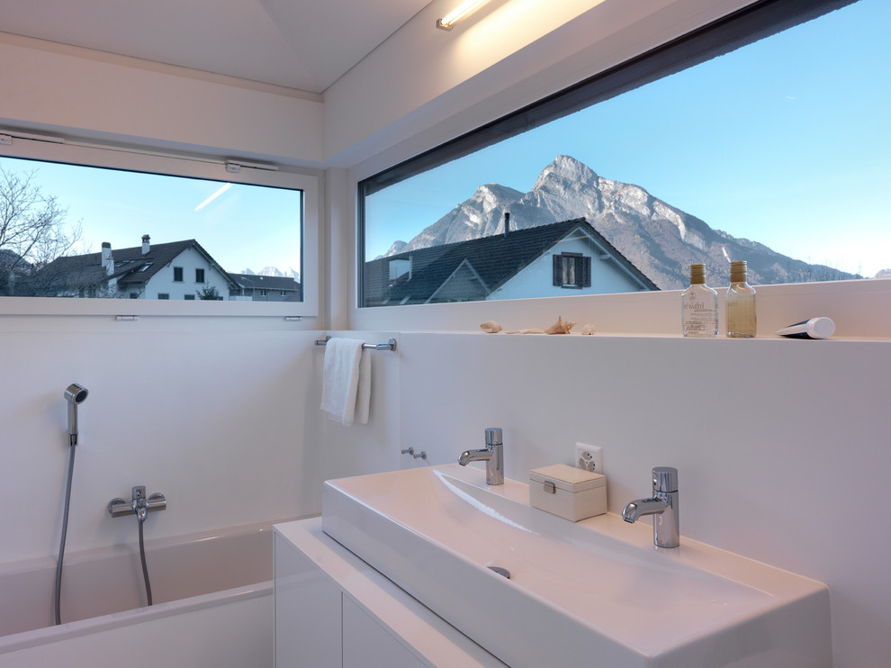Diseño de cuarto de baño contemporáneo pequeño con lavabo de seno grande, armarios con paneles lisos, puertas de armario blancas, bañera encastrada, combinación de ducha y bañera, paredes blancas y encimera de madera
