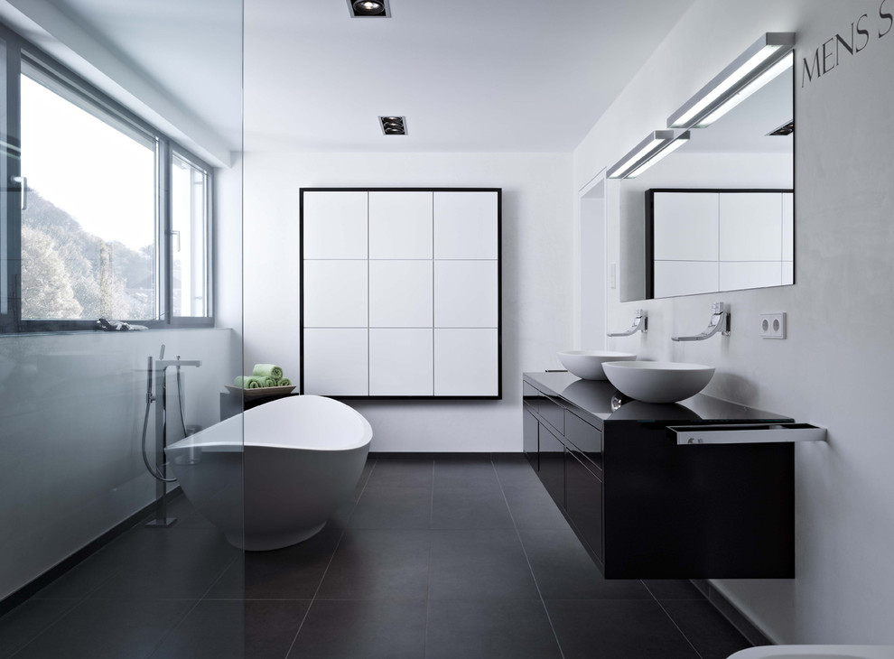 Réalisation d'une salle de bain principale design de taille moyenne avec un placard à porte plane, des portes de placard noires, un carrelage noir, un mur blanc et une vasque.