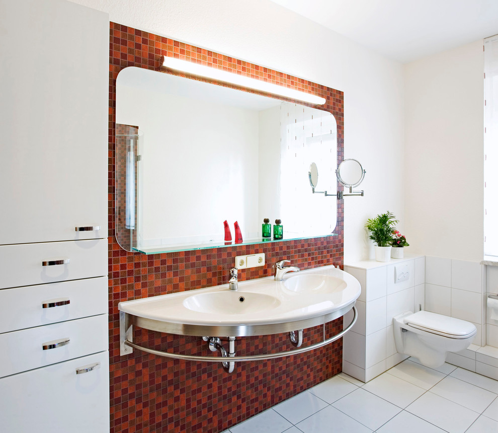 На фото: большая ванная комната в современном стиле с подвесной раковиной, плоскими фасадами, белыми фасадами, инсталляцией, разноцветной плиткой, плиткой мозаикой, белыми стенами и полом из керамической плитки