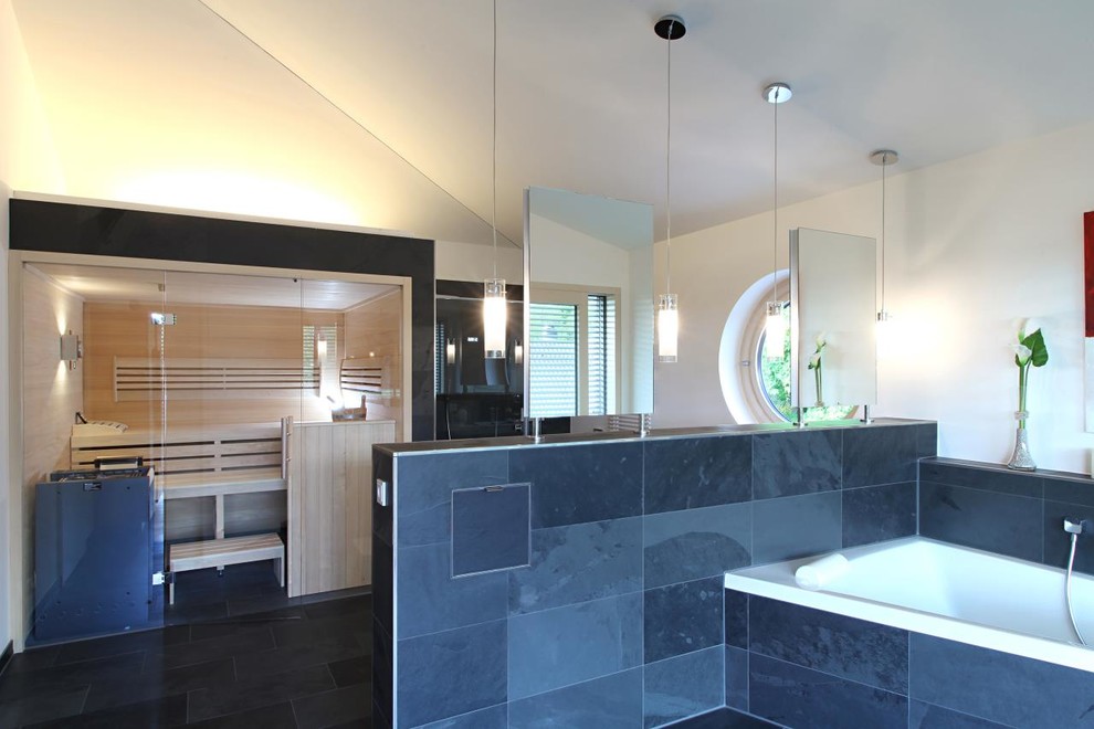 Modelo de sauna contemporánea, extra grande, con bañera empotrada, baldosas y/o azulejos negros, baldosas y/o azulejos de piedra, paredes blancas y suelo de pizarra
