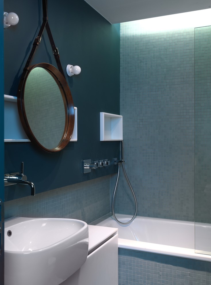 Idéer för att renovera ett litet funkis badrum, med en dusch/badkar-kombination, blå kakel, mosaik, blå väggar, släta luckor, vita skåp, ett fristående handfat och ett platsbyggt badkar