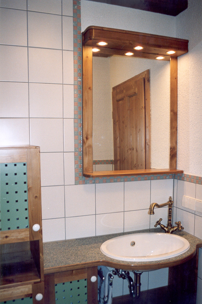 Farmhouse bathroom in Stuttgart with flat-panel cabinets, red cabinets, a vessel sink and granite worktops.