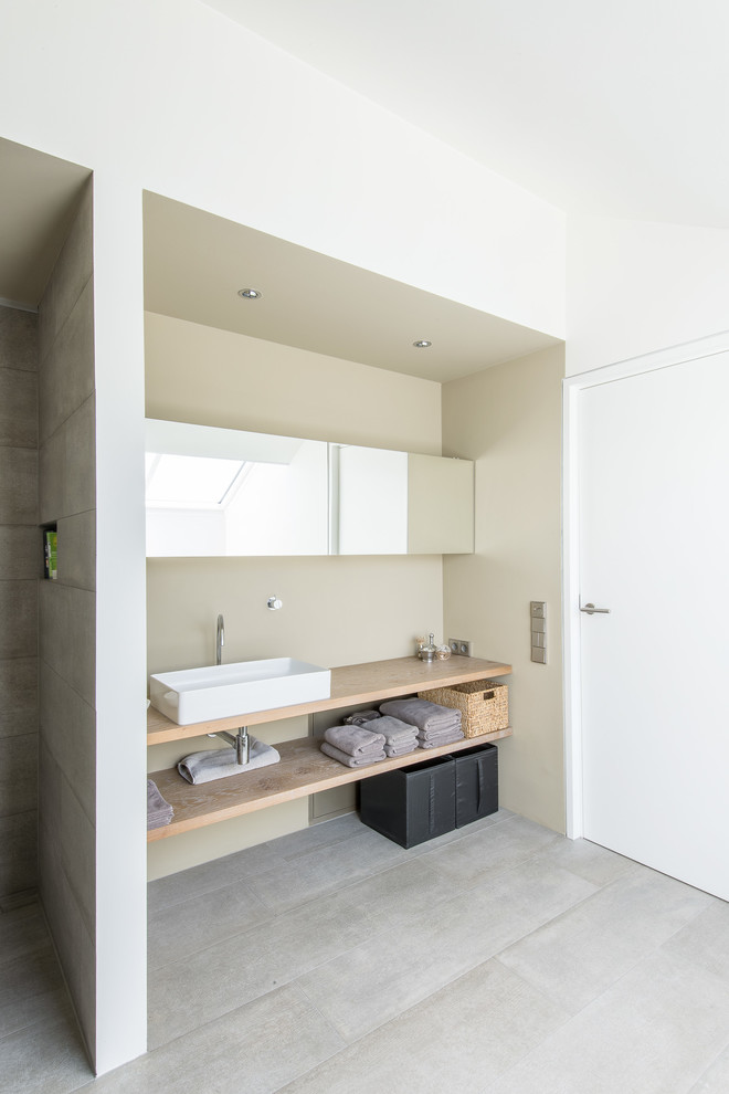 Cette image montre une grande douche en alcôve design avec un carrelage gris, des dalles de pierre, un mur beige, une vasque et un plan de toilette en bois.