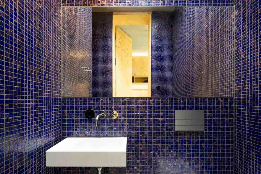 Foto på ett litet funkis badrum, med blå kakel, mosaik och ett väggmonterat handfat