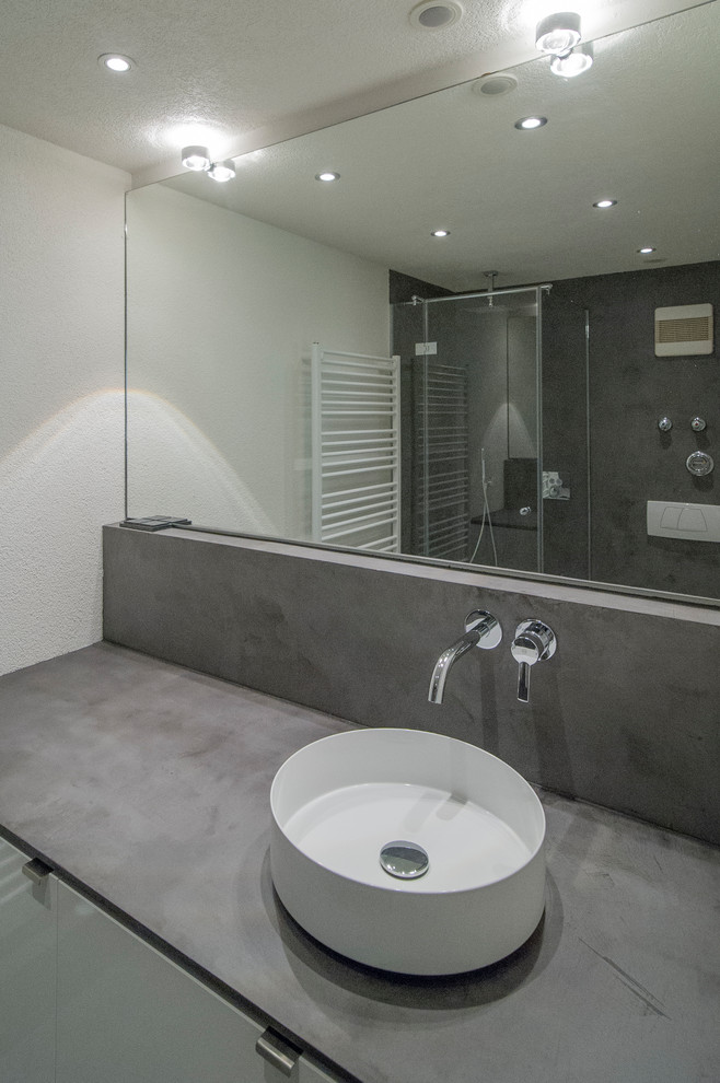 Idéer för att renovera ett litet funkis grå grått badrum med dusch, med släta luckor, vita skåp, en vägghängd toalettstol, grå kakel, grå väggar, betonggolv, ett fristående handfat, bänkskiva i betong och grått golv