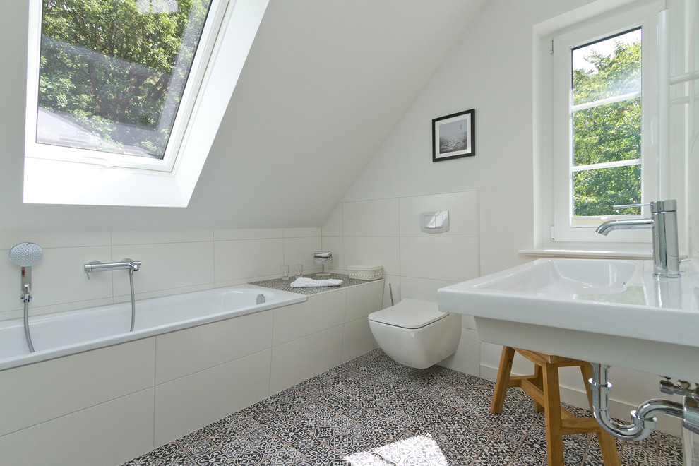 На фото: ванная комната среднего размера в современном стиле с накладной ванной, инсталляцией, белой плиткой, керамической плиткой, белыми стенами, полом из цементной плитки, душевой кабиной, подвесной раковиной и разноцветным полом с