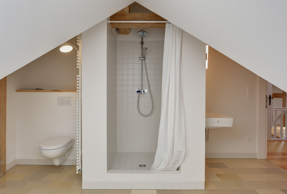 Foto de cuarto de baño actual de tamaño medio con lavabo suspendido, ducha empotrada, sanitario de pared, paredes blancas, baldosas y/o azulejos grises y aseo y ducha