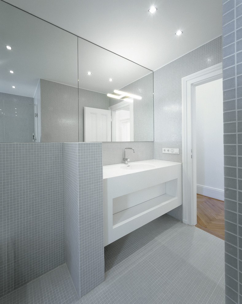 Modelo de cuarto de baño actual grande con armarios abiertos, puertas de armario blancas, baldosas y/o azulejos grises, baldosas y/o azulejos en mosaico, paredes grises, suelo con mosaicos de baldosas y lavabo integrado