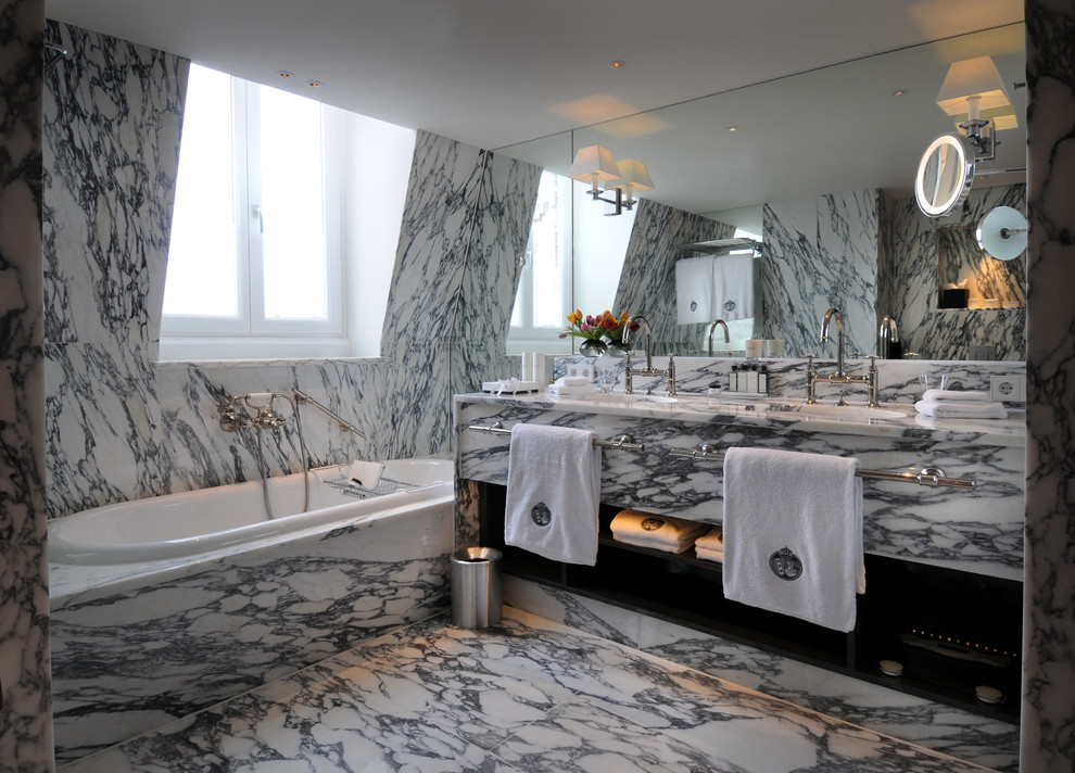 Diseño de cuarto de baño ecléctico de tamaño medio con encimera de mármol, bañera empotrada, baldosas y/o azulejos de piedra, suelo de mármol, armarios con paneles lisos y lavabo encastrado
