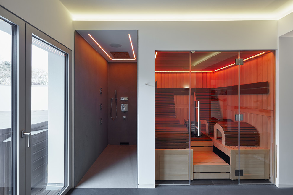 Imagen de sauna actual de tamaño medio con paredes blancas y suelo de cemento