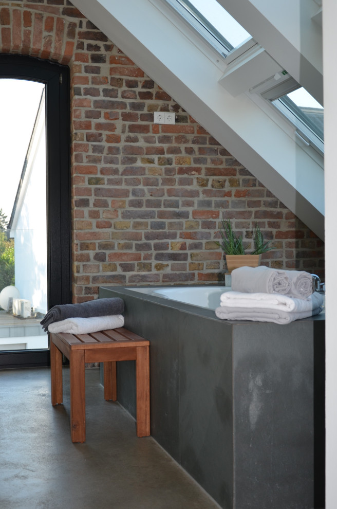 Inspiration for a medium sized industrial bathroom in Dusseldorf with a freestanding bath, concrete flooring, grey floors and brick walls.