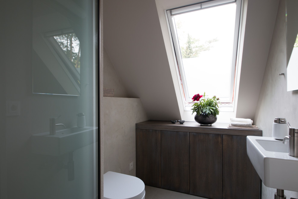 Cette image montre une grande salle de bain principale design en bois foncé avec un placard à porte plane, une baignoire posée, une douche à l'italienne, des dalles de pierre, un mur gris, un lavabo intégré, un plan de toilette en marbre et un sol gris.