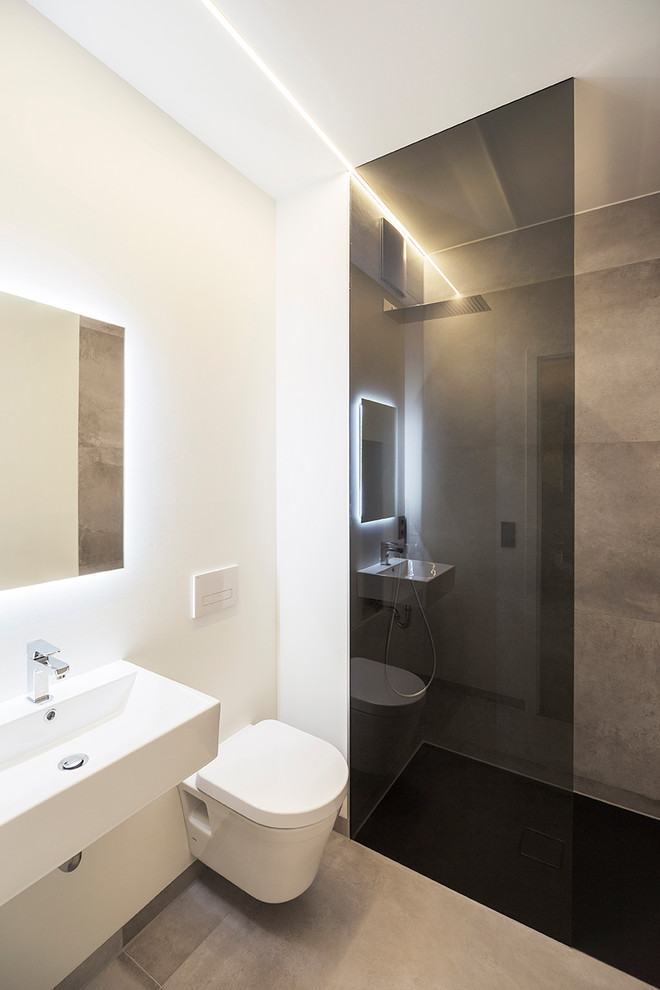 Foto de cuarto de baño actual pequeño con ducha a ras de suelo, sanitario de pared, paredes blancas, suelo de cemento, lavabo suspendido y suelo gris