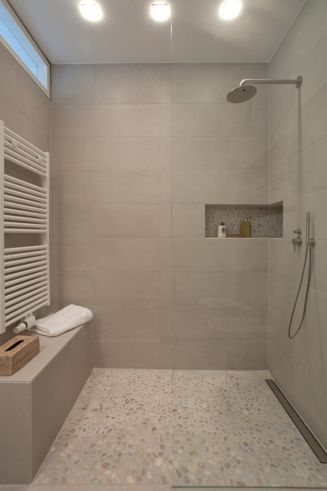 Réalisation d'une salle d'eau design de taille moyenne avec une douche à l'italienne, WC suspendus, un carrelage gris, des carreaux de céramique, un mur blanc, un sol en galet et une vasque.