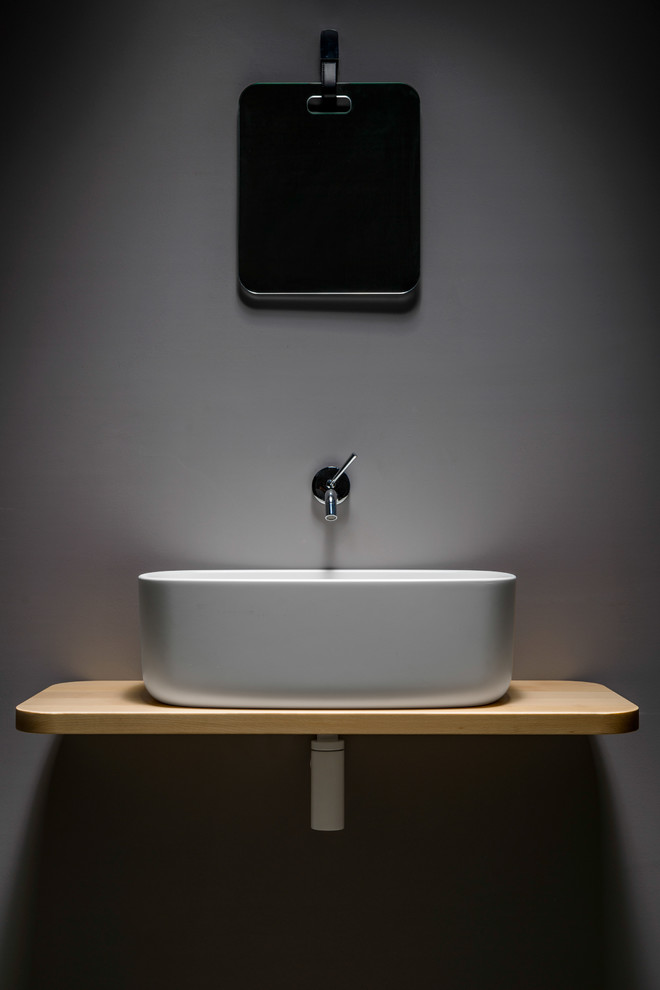 Cette photo montre une salle de bain moderne en bois clair avec un mur gris et une vasque.