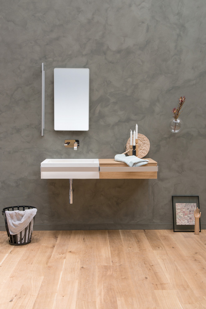 Cette photo montre une salle de bain moderne en bois clair avec un carrelage blanc, un mur gris, parquet clair, un lavabo suspendu et un plan de toilette en surface solide.