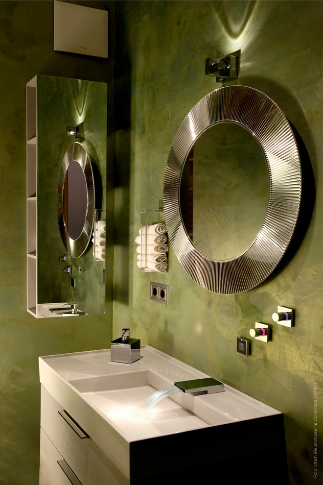 Foto de cuarto de baño actual con armarios con paneles lisos, puertas de armario grises, paredes verdes y lavabo integrado