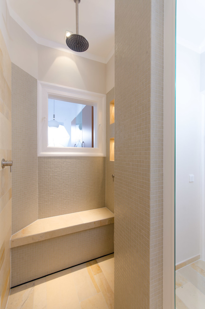 Bild på ett litet funkis badrum med dusch, med beige kakel, beige väggar, släta luckor, vita skåp, en öppen dusch, en vägghängd toalettstol, kakelplattor, kalkstensgolv, ett fristående handfat, bänkskiva i kalksten och beiget golv