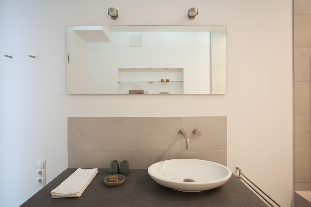 Exempel på ett mellanstort modernt badrum med dusch, med en kantlös dusch, en vägghängd toalettstol, grå kakel, keramikplattor, vita väggar, klinkergolv i småsten och ett fristående handfat