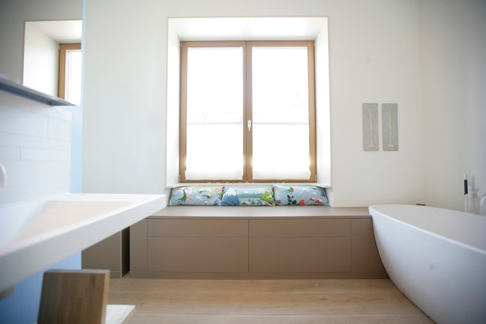Источник вдохновения для домашнего уюта: большая главная ванная комната в современном стиле с отдельно стоящей ванной, душем без бортиков, белой плиткой, керамической плиткой, светлым паркетным полом, подвесной раковиной, столешницей из искусственного камня, бежевым полом, открытым душем, белой столешницей, сиденьем для душа, тумбой под две раковины и подвесной тумбой