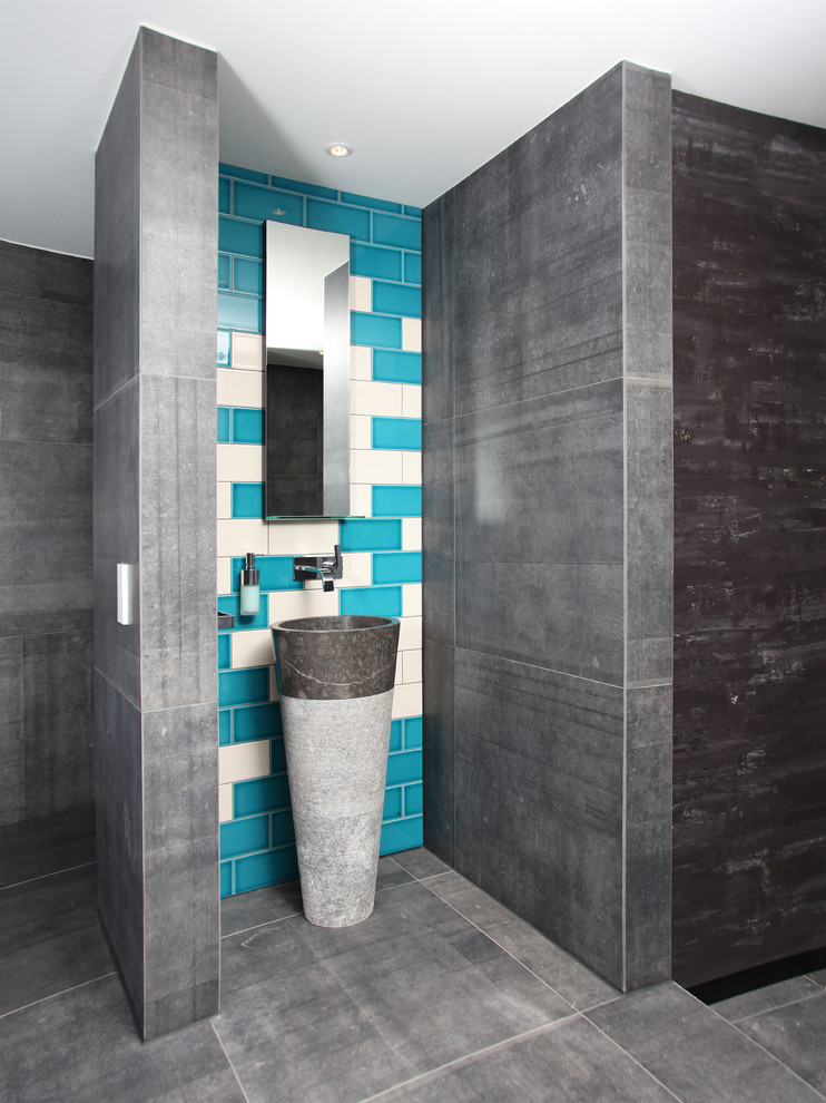 На фото: ванная комната в современном стиле с плиткой из листового камня, бетонным полом и раковиной с пьедесталом с