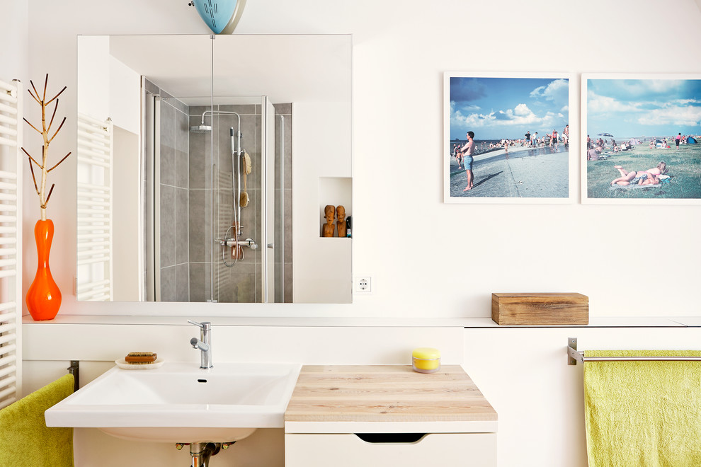 Bild på ett mellanstort funkis badrum, med släta luckor, beige skåp, en hörndusch, vita väggar, ett väggmonterat handfat och träbänkskiva