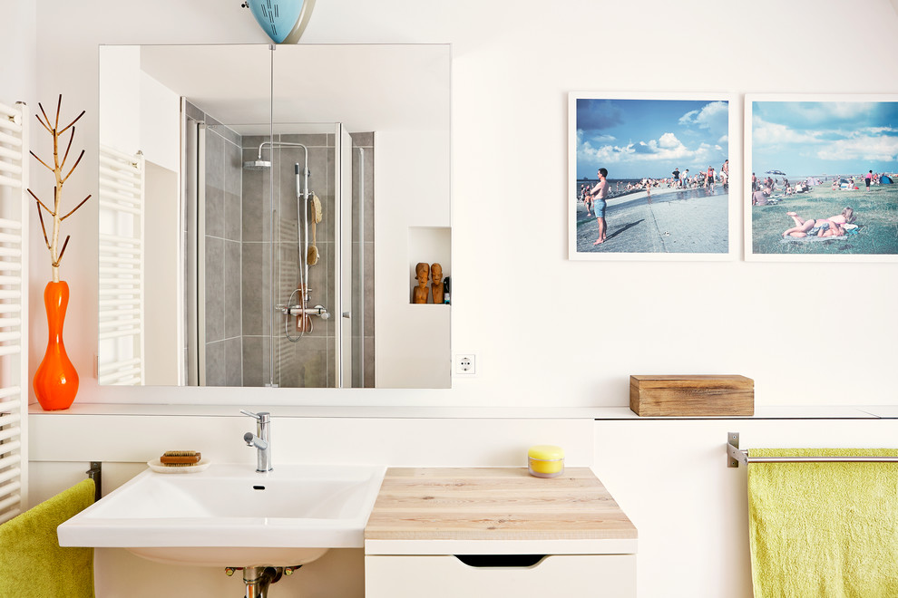 Example of a mid-sized trendy corner shower design in Hamburg with flat-panel cabinets, beige cabinets, white walls, a wall-mount sink and wood countertops