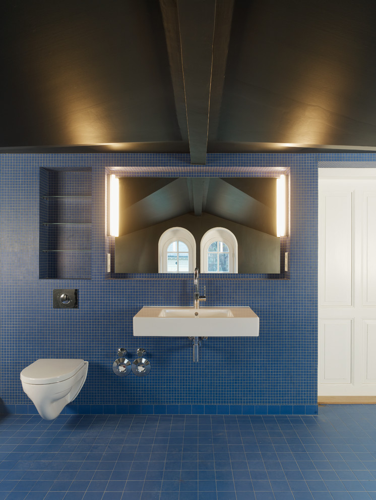 Großes Badezimmer mit Wandtoilette, blauen Fliesen, Mosaikfliesen und Wandwaschbecken in Berlin