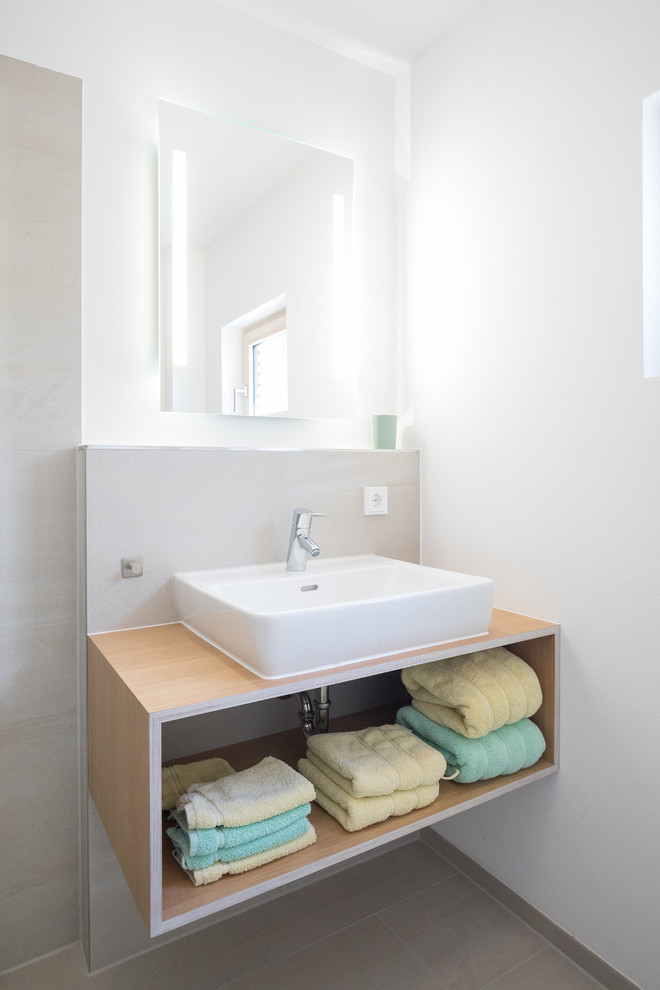 Modelo de cuarto de baño nórdico de tamaño medio con armarios abiertos, baldosas y/o azulejos grises, paredes blancas, lavabo sobreencimera y encimeras marrones