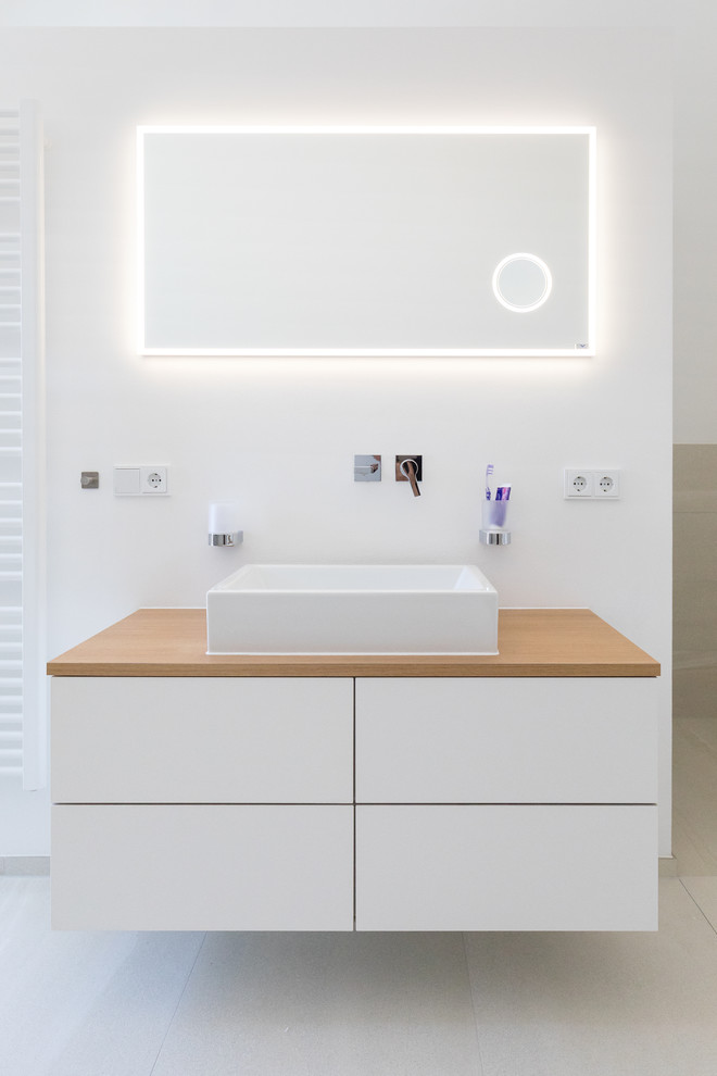 Diseño de cuarto de baño nórdico de tamaño medio con armarios abiertos, baldosas y/o azulejos grises, paredes blancas, lavabo sobreencimera y encimeras marrones