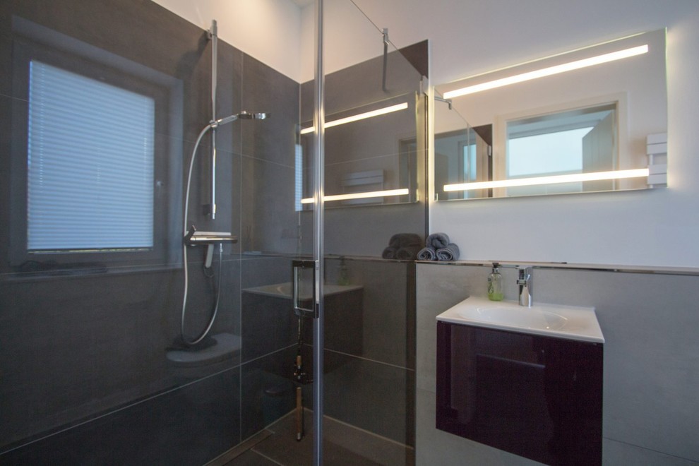 Foto på ett mellanstort funkis vit badrum med dusch, med släta luckor, svarta skåp, en kantlös dusch, svart kakel, stenkakel, grå väggar, klinkergolv i porslin, ett fristående handfat, brunt golv och med dusch som är öppen