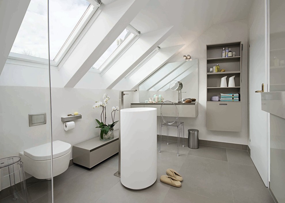 Diseño de cuarto de baño actual de tamaño medio con lavabo con pedestal, armarios abiertos, puertas de armario grises, paredes blancas, suelo de pizarra y sanitario de pared