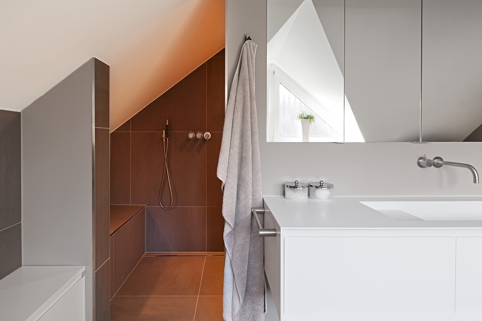 Foto på ett stort funkis badrum, med ett integrerad handfat, släta luckor, grå väggar, vita skåp, en dusch i en alkov, grå kakel och bänkskiva i akrylsten