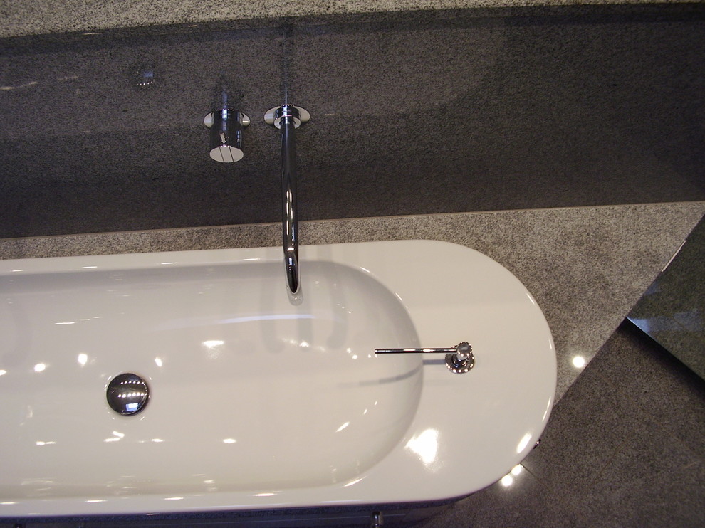 Bild på ett stort funkis grå grått en-suite badrum, med släta luckor, vita skåp, ett platsbyggt badkar, en dusch/badkar-kombination, en vägghängd toalettstol, vit kakel, glaskakel, ett fristående handfat, granitbänkskiva, orange golv och med dusch som är öppen