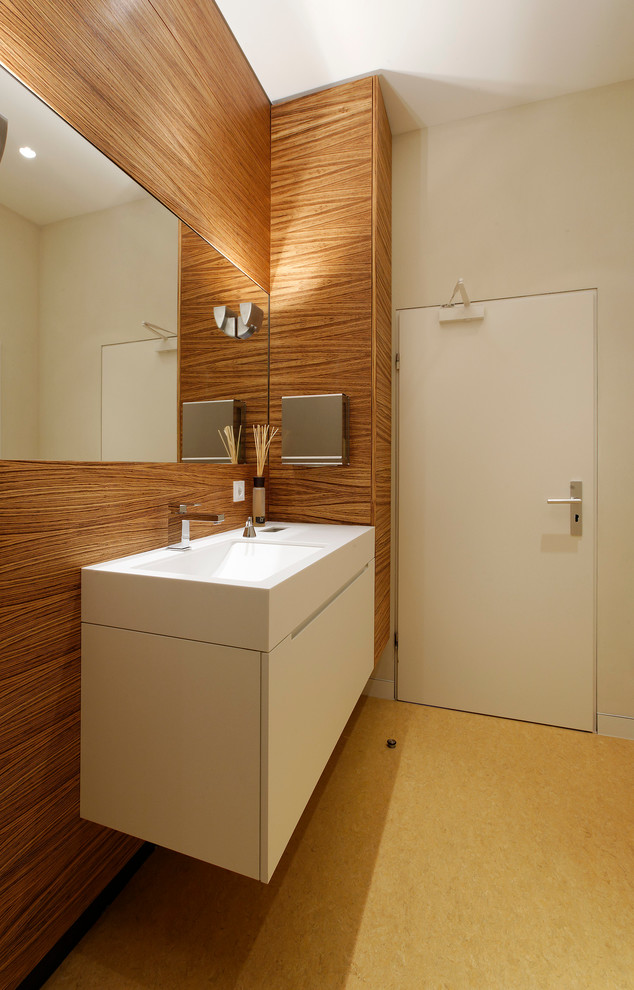 Immagine di una stanza da bagno contemporanea con lavabo sottopiano, ante lisce, ante bianche, pareti beige e top in superficie solida