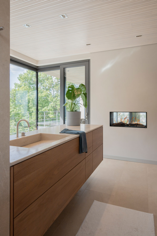 Example of a large minimalist 3/4 beige tile and limestone tile limestone floor, beige floor, single-sink and wood ceiling bathroom design in Other with brown cabinets, a wall-mount toilet, beige walls, an integrated sink, limestone countertops, beige countertops and a built-in vanity