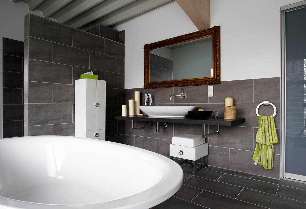 Inspiration for an expansive modern ensuite bathroom in Other with flat-panel cabinets, white cabinets, a freestanding bath, a built-in shower, a wall mounted toilet, grey tiles, stone tiles, white walls, slate flooring, a vessel sink, laminate worktops, grey floors, an open shower and black worktops.