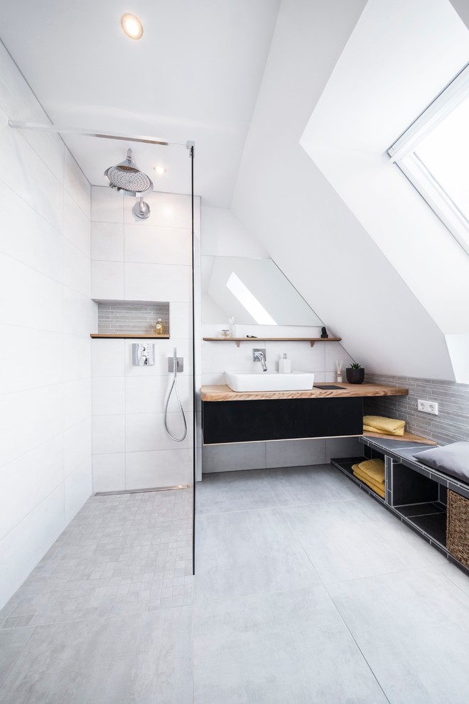 На фото: ванная комната среднего размера в современном стиле с настольной раковиной, серой плиткой, керамической плиткой, белыми стенами, полом из керамической плитки, душевой кабиной, черными фасадами, столешницей из дерева и открытым душем с