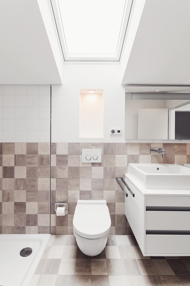 Photo of a small contemporary bathroom in Frankfurt with flat-panel cabinets, white cabinets, ceramic tiles, ceramic flooring, a vessel sink, a wall mounted toilet, beige tiles, brown tiles and brown walls.