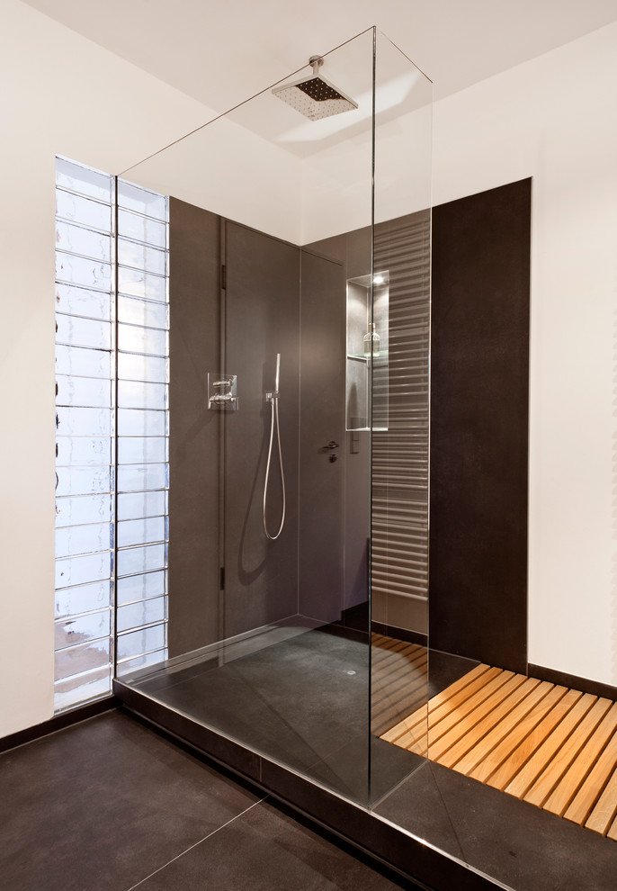 Photo of a contemporary bathroom in Bremen with a corner shower, black tiles, stone slabs and white walls.