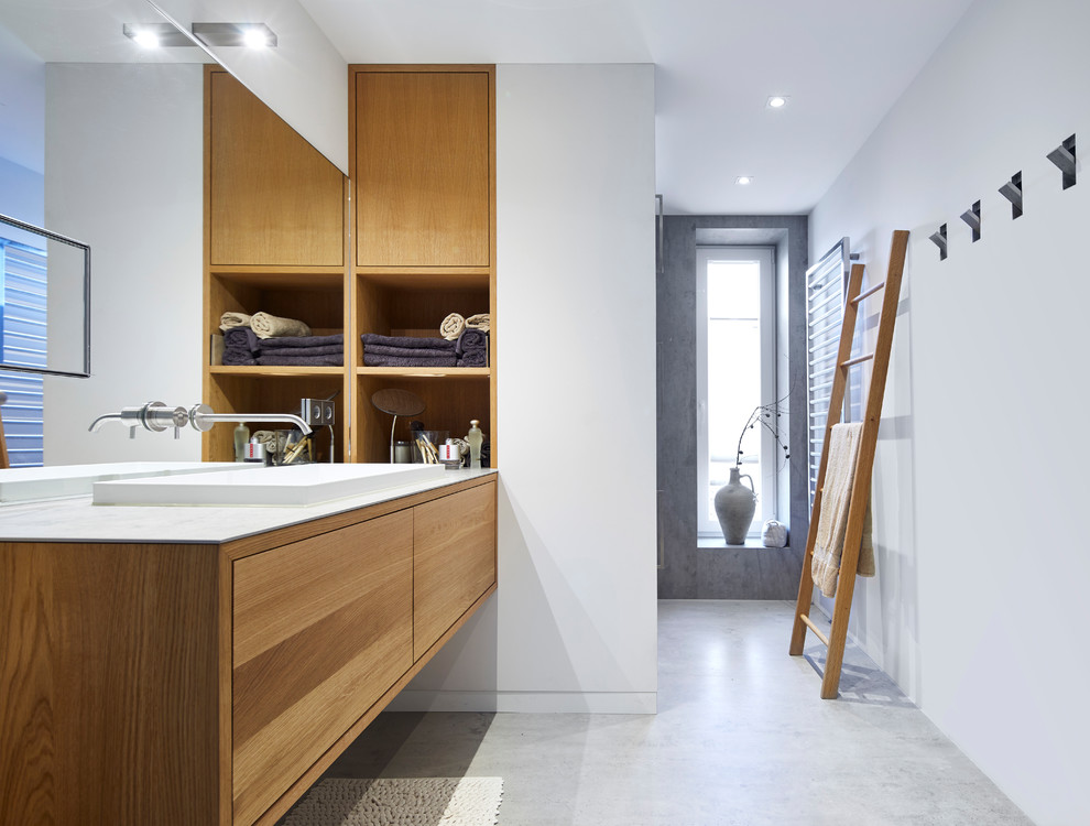 Idéer för att renovera ett stort funkis grå grått en-suite badrum, med släta luckor, skåp i mellenmörkt trä, vita väggar, betonggolv, ett fristående handfat, grått golv, vit kakel, spegel istället för kakel, bänkskiva i glas, en kantlös dusch och med dusch som är öppen