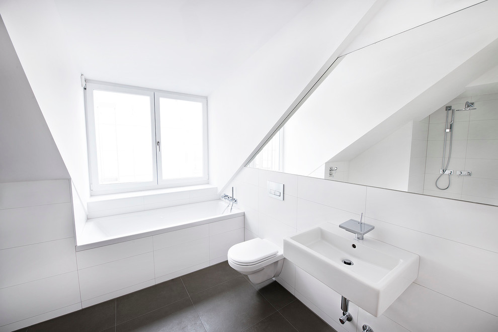 Inspiration for a contemporary bathroom in Munich with a built-in bath, a wall mounted toilet, white tiles, ceramic tiles, white walls and a wall-mounted sink.