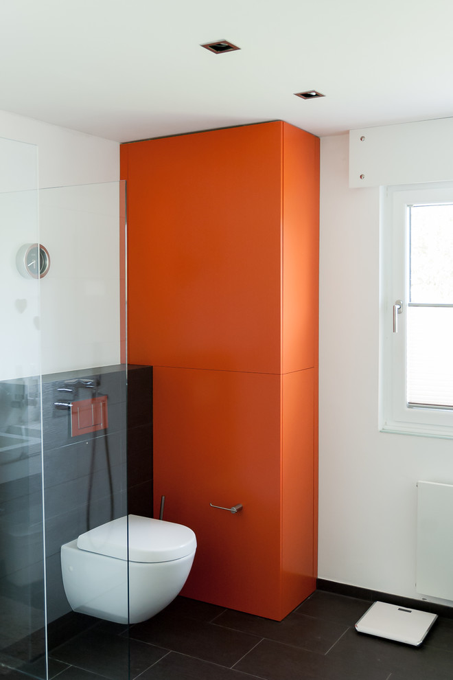 Inspiration för moderna badrum, med släta luckor, orange skåp, vita väggar och svart golv