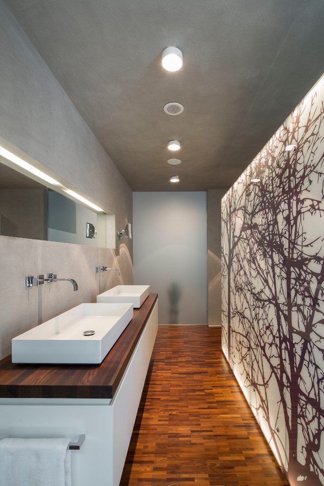 Exempel på ett mellanstort modernt badrum, med släta luckor, vita skåp, grå väggar, ett fristående handfat, träbänkskiva, brunt golv och mörkt trägolv