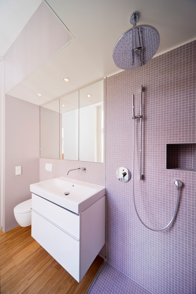 Idéer för att renovera ett litet badrum med dusch, med släta luckor, vita skåp, en kantlös dusch, en vägghängd toalettstol, mosaik, vita väggar, mellanmörkt trägolv, ett fristående handfat, brunt golv och med dusch som är öppen