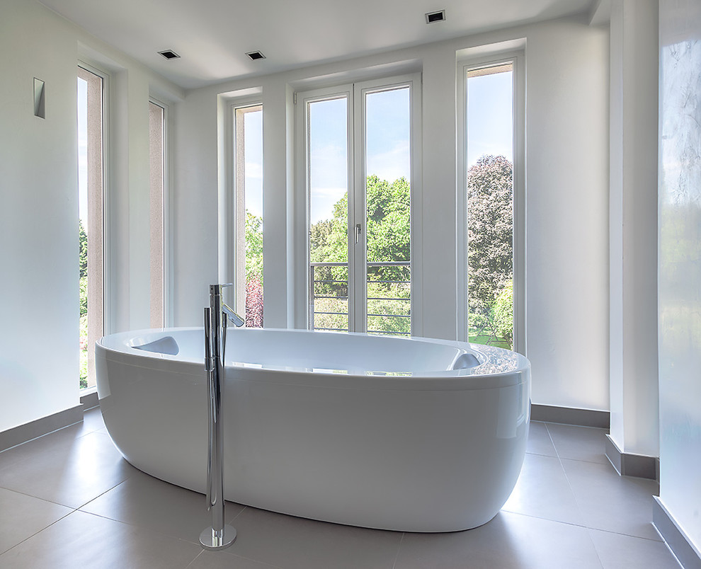 Idée de décoration pour une grande salle de bain design avec une baignoire indépendante, un mur blanc et une fenêtre.