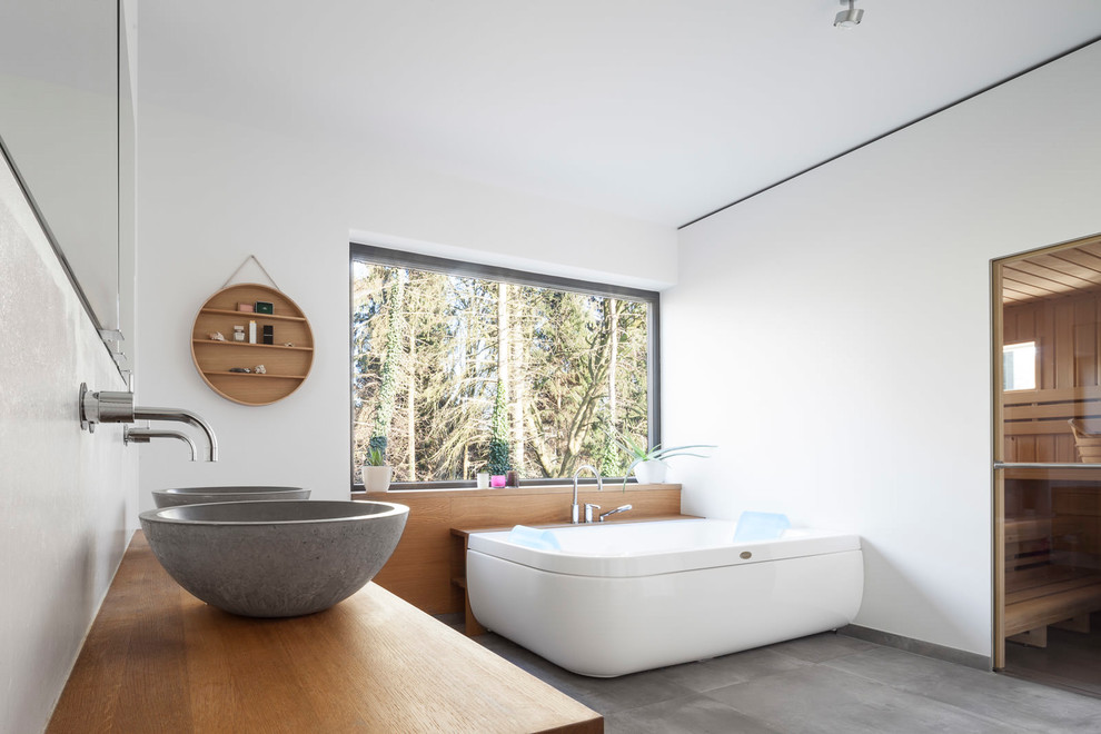 Mittelgroße Moderne Sauna mit freistehender Badewanne, weißer Wandfarbe, Betonboden, Aufsatzwaschbecken und grauem Boden in Hamburg